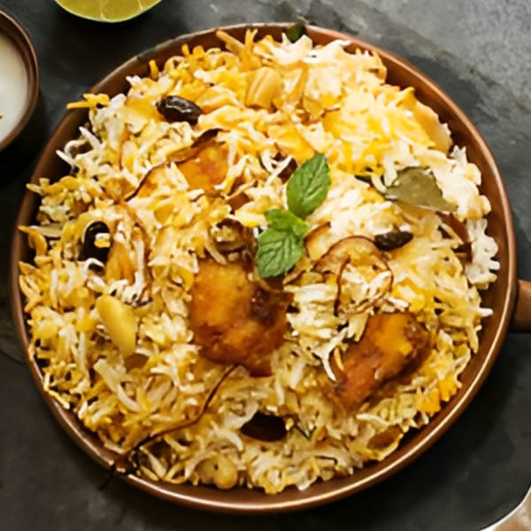 A close-up of Desi Chowrastha's chicken biryani, garnished with mint, cashews, and raisins.