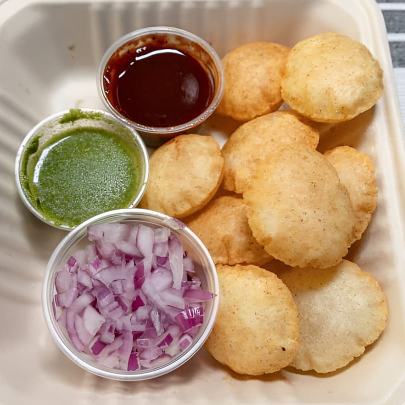 Pani Puri with small cups of green chutney, tamarind sauce, and diced red onions.